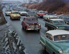 many old cars are driving down the road