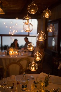 the table is set for dinner with many lights hanging from it's centerpieces