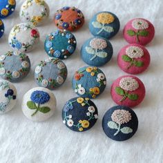 there are many different types of buttons on the table together, including one with flowers and leaves