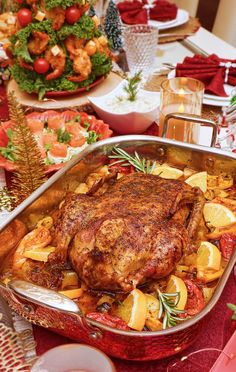 a large roasting pan filled with food on top of a red cloth covered table