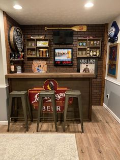 a bar with three stools in front of it and several beer signs on the wall