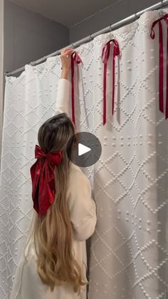 a woman in white shirt and red bow tie standing next to shower curtain with red ribbon on it