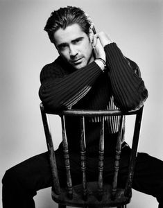 a black and white photo of a man sitting in a chair with his hands on his head