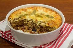 a casserole with meat and vegetables in a white dish on a red and white napkin