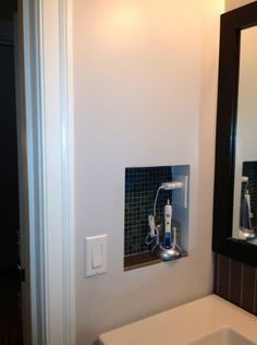 a bathroom with a sink, mirror and soap dispenser on the wall