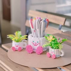 some plastic pens and pencils are sitting on a table with flowers in vases