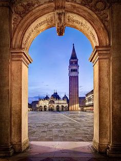 an archway leading to a building with a clock tower in the background