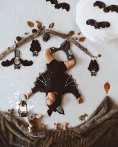 a person laying on the ground surrounded by fake bats and other halloween decorations, including pumpkins