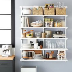 the shelves are filled with dishes, cups and other kitchen items in baskets on top of them