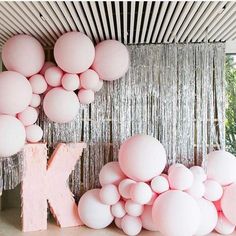 pink balloons are hanging from the ceiling in front of a wall with letters and streamers