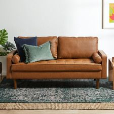 a brown leather couch sitting on top of a blue rug next to a wooden table