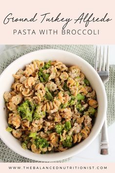 a white bowl filled with pasta and broccoli on top of a green place mat