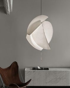 a white lamp hanging from the ceiling next to a brown chair and radiator