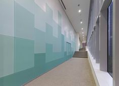 a long hallway with blue and green walls next to a set of stairs in an office building