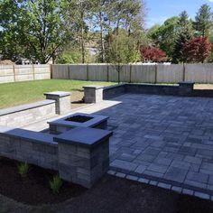 an outdoor fire pit in the middle of a yard with two benches on each side