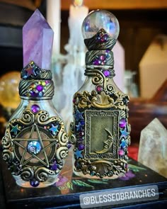 two glass bottles are sitting on a table next to each other with crystals in them