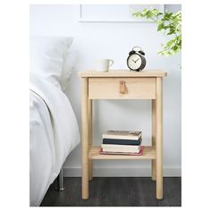 a bedside table with books and an alarm clock on the nightstand next to a bed