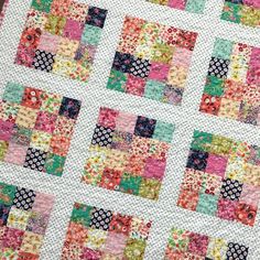 a close up of a patchwork quilt on a table top with pink, green and blue squares