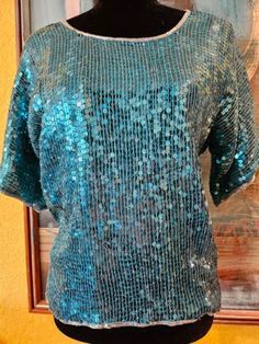 "This stunning teal sequins vintage top is the perfect next addition to your wardrobe collection! This silk and sequins top is made by Royal Feelings. It is a deep teal in color  and is covered all over in gorgeous sequins and bead trim! This top is in amazing vintage condition NWT to include a pack of extra beads attached.  Perfect for both casual and formal outfits alike. This is a fun, hip and trendy retro sequins top to wear with jeans and or dressed up to go to  a fromal event!  Get this top as a gift for yourself or for someone in your life who loves vintage sequins fashion. Length 23\" Bust 38\" Sleeve 10.5\"  Sleeve Opening 6.5\"  Waist 36\" My photos are shots of the original item. Light or dark spots are reflections caused by the lighting. Color deviations can occur depending on Blue Sequin Top, 80s Top, Navy Blue Purse, Sequins Top, Teal Blouse, Fashion 80s, Sparkly Top, Sequin Blouse, Formal Outfits