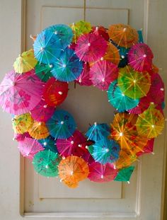 a wreath made out of umbrellas hanging from the side of a door with lights on it