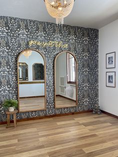 an empty room with three mirrors on the wall and a chandelier hanging from the ceiling