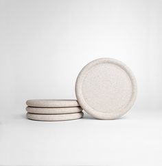 three white plates stacked on top of each other in front of a white wall and floor