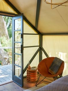 a bed sitting inside of a tent next to a window with an open book on it