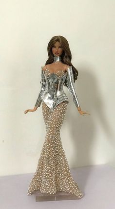 a barbie doll wearing a silver and gold dress with sequins on it's body