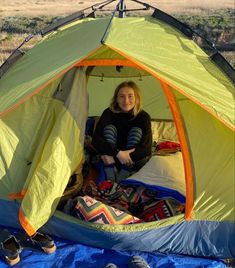 a woman sitting in a tent on top of a blue blanket