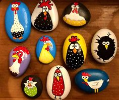 painted rocks with chickens, roosters and other animals on them sitting on a table