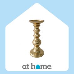 a gold candle holder sitting on top of a blue and white sign that says at home