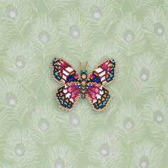 a beaded butterfly sitting on top of a green wall next to a flower pattern