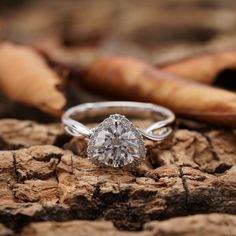 a diamond ring sitting on top of a piece of wood next to an orange leaf