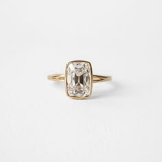 an engagement ring with a square cut diamond in the center, on a white background