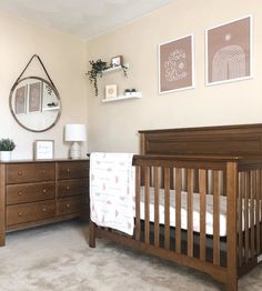 a baby's room with a crib, dresser and mirror on the wall