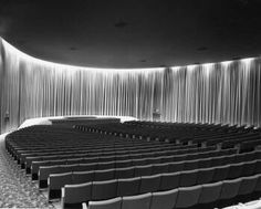 an empty auditorium with rows of seats in front of a curtained wall and floor