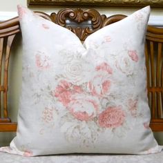 a white and pink pillow sitting on top of a wooden chair next to a mirror