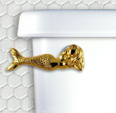 a gold fish shaped object on the side of a toilet