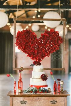 a heart shaped cake sitting on top of a table next to candles and flowers in vases