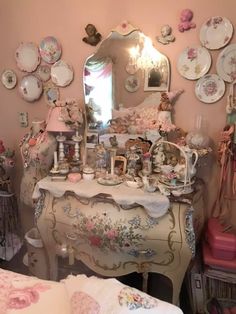 a bedroom with a dresser, mirror and many plates on the wall above it that are covered in pink flowers