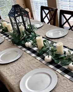 the table is set with white plates and candles