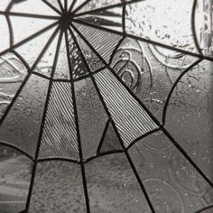 a close up of a stained glass window with water drops on it and the bottom part of an umbrella