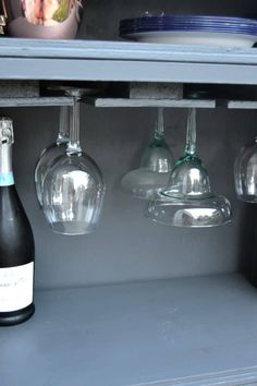 three wine glasses are hanging from the shelf