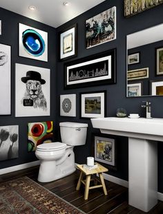 a white toilet sitting next to a sink in a bathroom under pictures on the wall