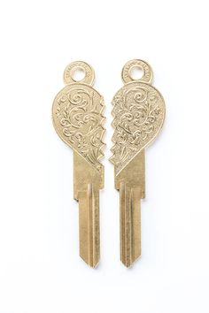 two gold heart shaped keys are shown on a white background, with the key to each other