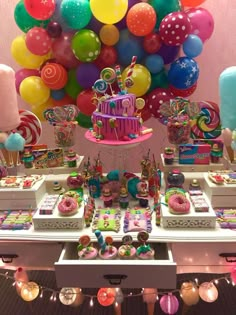 a table filled with lots of colorful balloons and desserts on top of it's tables