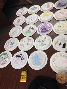 many paper plates have been decorated with children's drawings on them and are sitting on the table