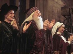 three men in robes and hats applauding each other