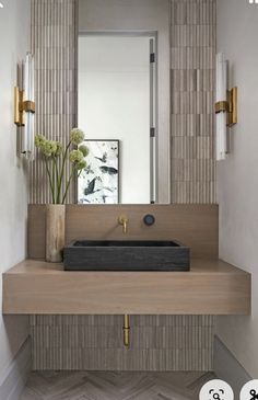 a bathroom sink sitting under a mirror next to a wall mounted faucet with flowers in it