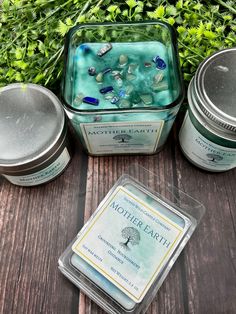 three tins with different types of items in them sitting on a table next to some plants